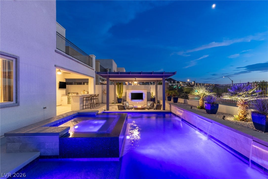 743 Glowing Horizon Street, Henderson, NV 89052 An illuminated backyard oasis boasts a resort-style pool, spa, outdoor kitchen, and a covered lounge area with a fire pit.