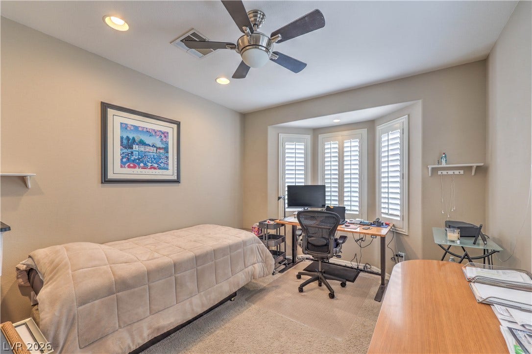 10298 Profeta Court, Las Vegas, NV 89135 A well-lit bedroom featuring a functional workspace and a distinctive bay window with plantation shutters.
