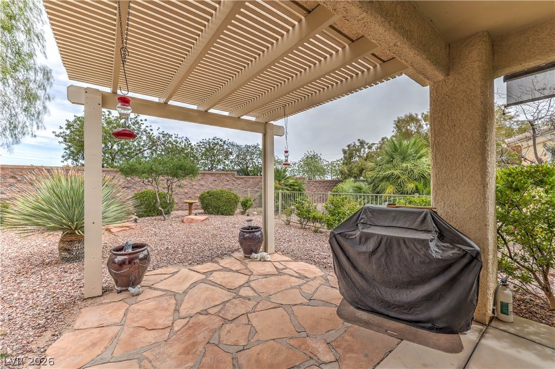 10298 Profeta Court, Las Vegas, NV 89135 A spacious backyard patio features a pergola, flagstone, and gravel landscaping.