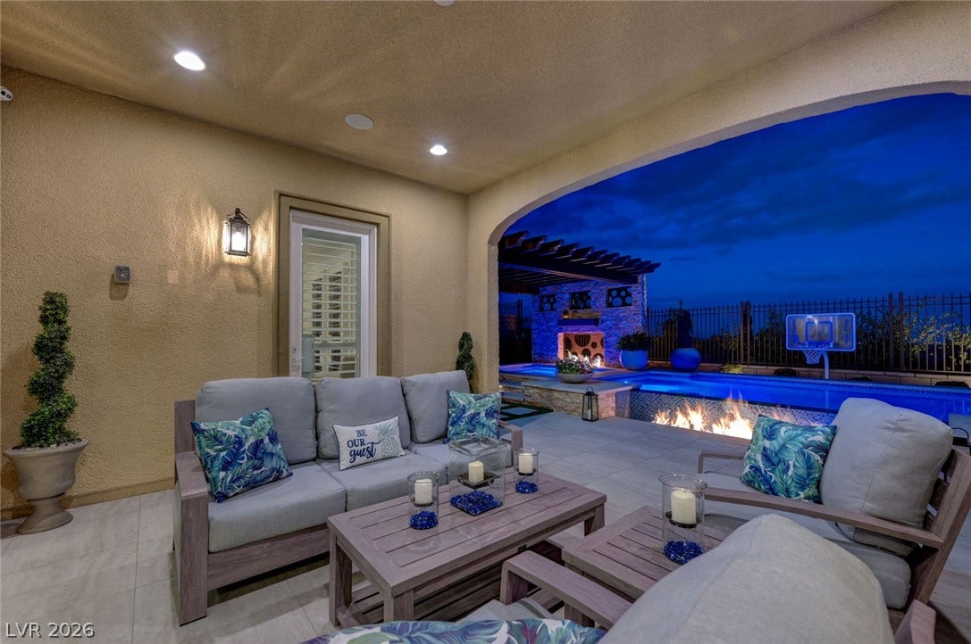 274 Evante Street, Las Vegas, NV 89138 An inviting covered patio with a cozy seating area and a vibrant fire pit next to a sparkling pool.