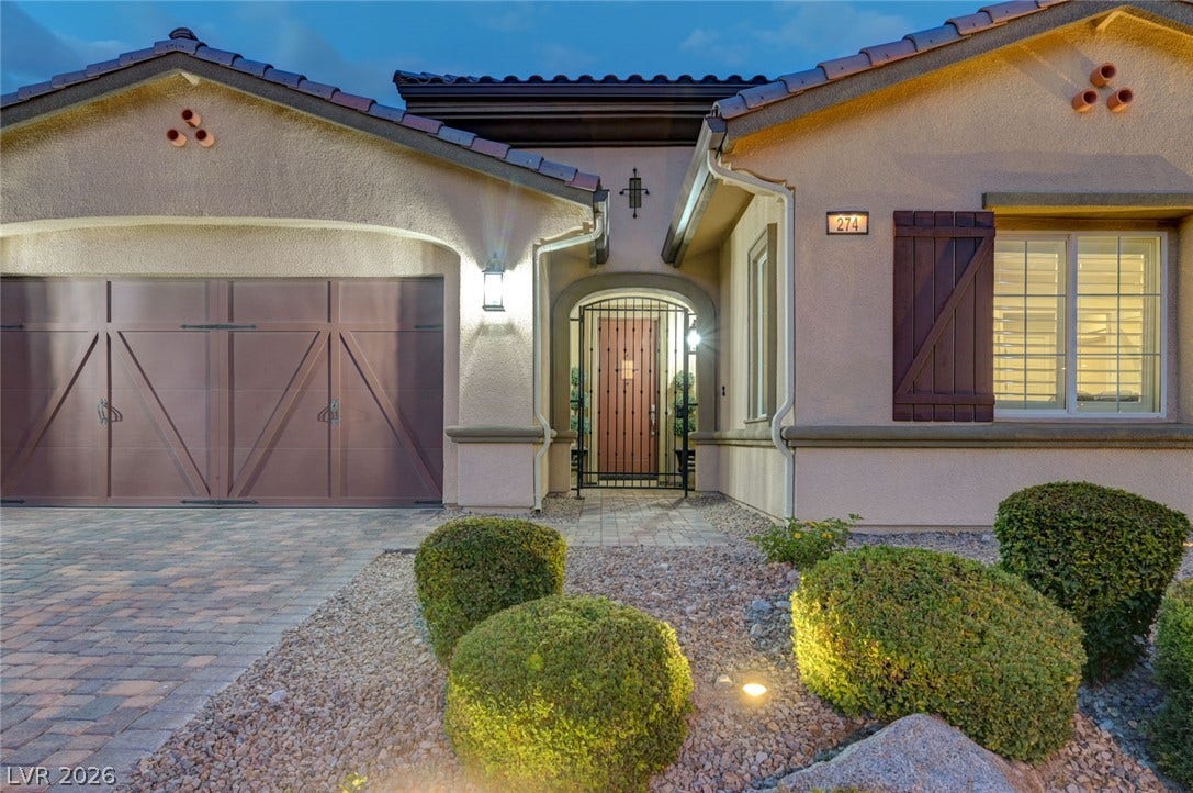 274 Evante Street, Las Vegas, NV 89138 A welcoming entry, with a paver driveway, elegant arched entryway, and well-maintained shrubbery, beckons residents and guests.