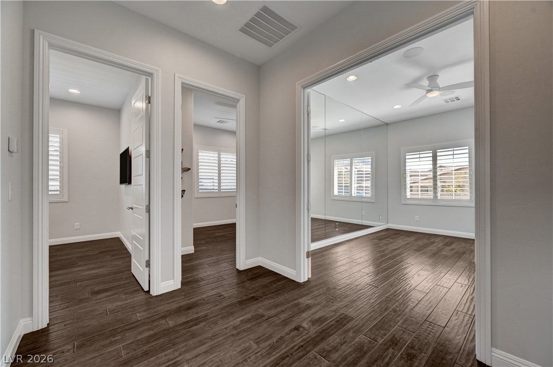 274 Evante Street, Las Vegas, NV 89138 Rich wood floors seamlessly connect a versatile den featuring full-height mirrors with nearby bedrooms.