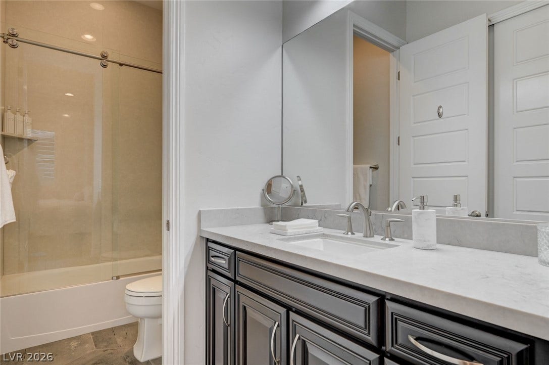 274 Evante Street, Las Vegas, NV 89138 A well-appointed bathroom features a dark wood vanity with a white countertop and a sleek glass-enclosed shower.