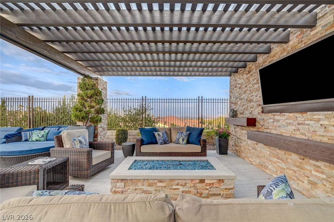 274 Evante Street, Las Vegas, NV 89138 An inviting outdoor living area with a louvered pergola and a stone-clad wall with an integrated fire pit.