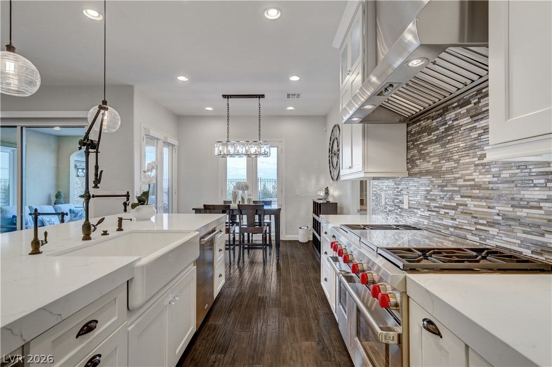 274 Evante Street, Las Vegas, NV 89138 A well-appointed kitchen features rich hardwood flooring, a gas range with a substantial hood, and an inviting dining area beyond.