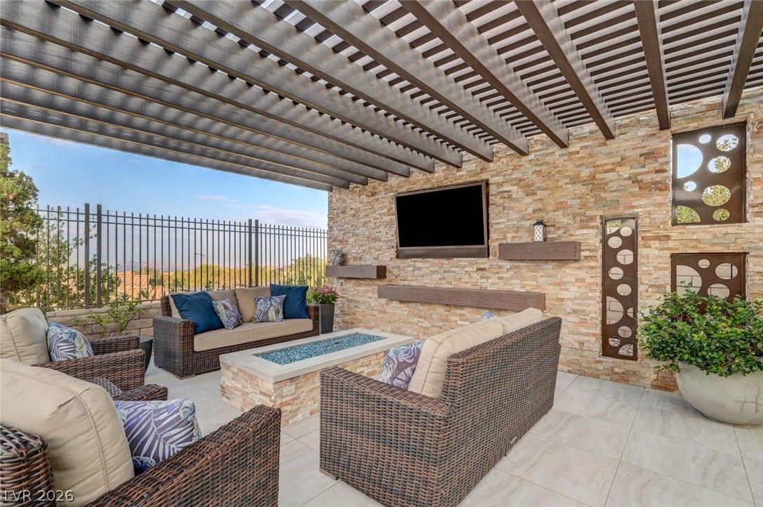 274 Evante Street, Las Vegas, NV 89138 An inviting outdoor living space features a stone fire pit, built-in television, and an open pergola overhead.