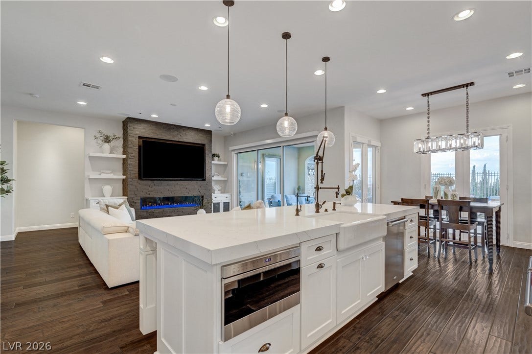 274 Evante Street, Las Vegas, NV 89138 An open-concept living space features dark wood flooring, a modern fireplace, and a spacious kitchen island with a farmhouse sink.