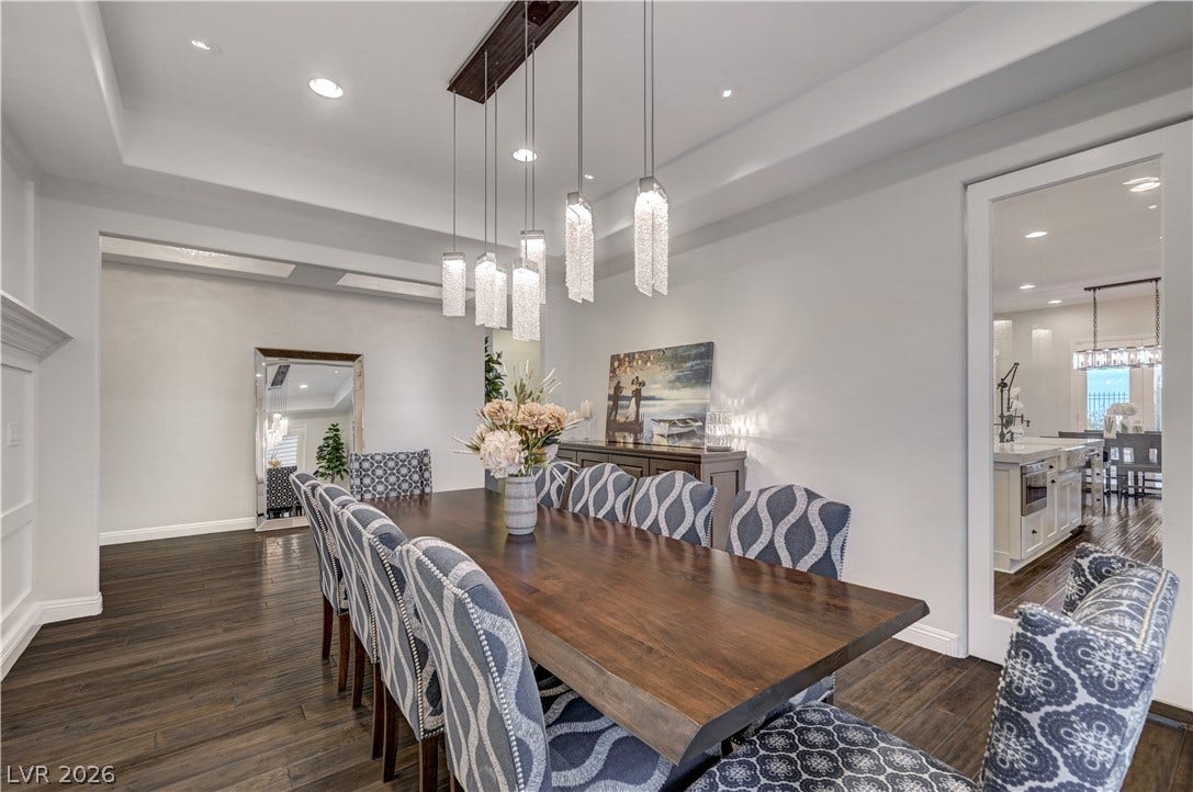274 Evante Street, Las Vegas, NV 89138 A refined dining space features rich wood flooring and a modern chandelier, flowing seamlessly into the adjacent kitchen.