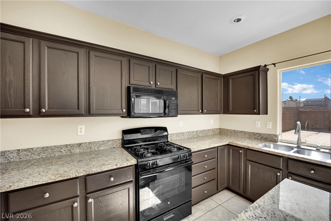 5823 Golden Wing Street, Las Vegas, NV 89113 Functional kitchen with dark cabinetry, granite countertops, and modern appliances.