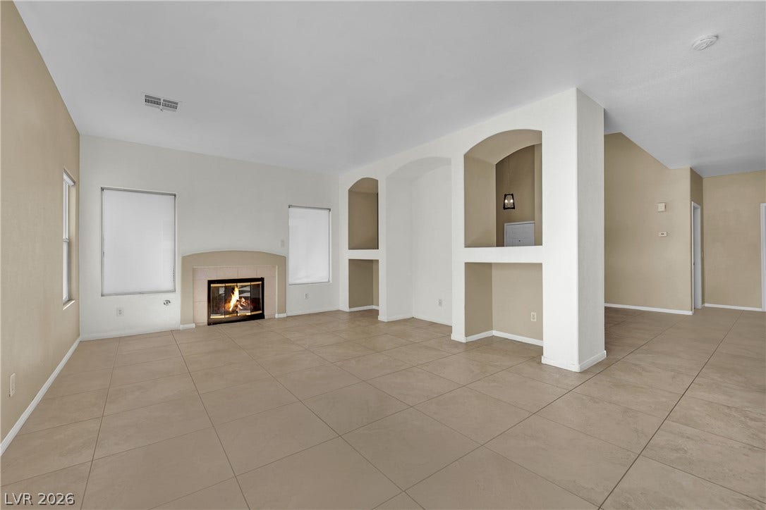 5823 Golden Wing Street, Las Vegas, NV 89113 A well-lit living area features a charming fireplace, built-in niches, and practical tile flooring throughout.