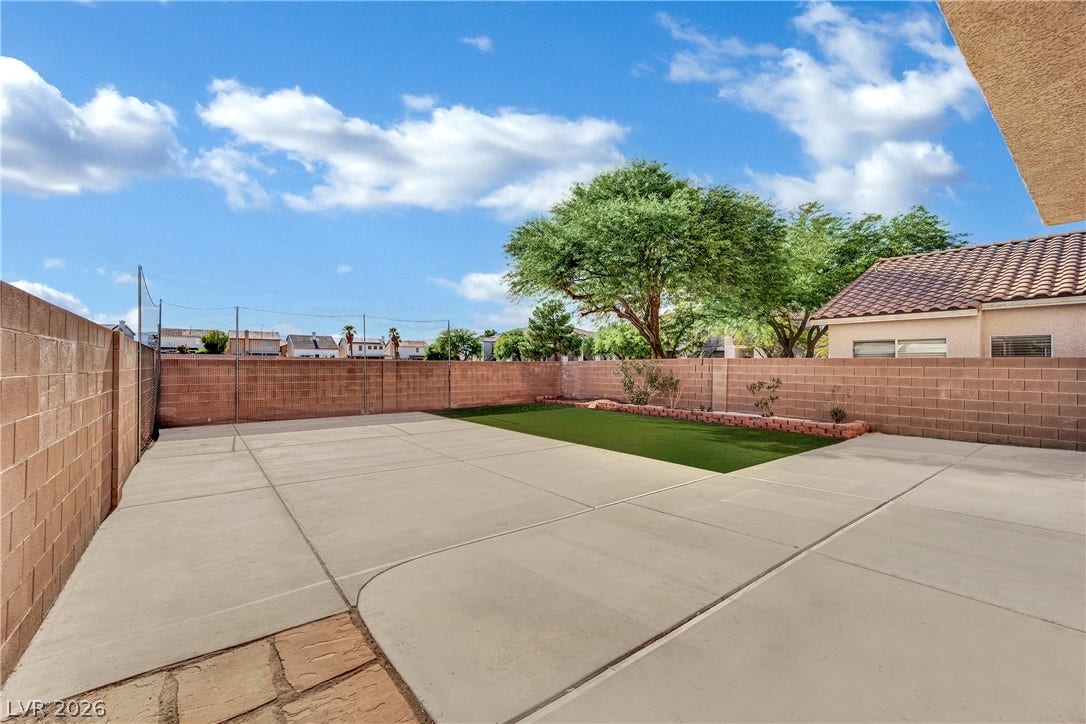 5823 Golden Wing Street, Las Vegas, NV 89113 A spacious, paved backyard with a patch of green turf, ideal for outdoor leisure.