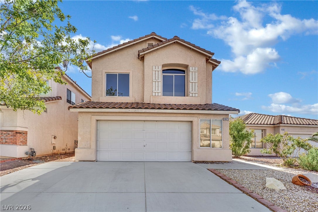 5823 Golden Wing Street, Las Vegas, NV 89113 A traditional two-story home features a tiled roof, stucco exterior, and an attached two-car garage with a wide concrete driveway.