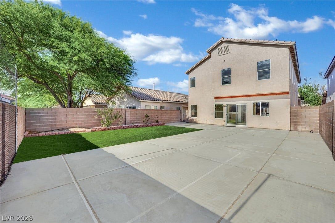 5823 Golden Wing Street, Las Vegas, NV 89113 A spacious backyard with mature trees, a concrete patio, and a neatly manicured lawn awaits your personal touch.