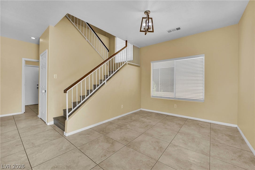 5823 Golden Wing Street, Las Vegas, NV 89113 A well-lit living area features an open staircase, tile flooring, and a large window.