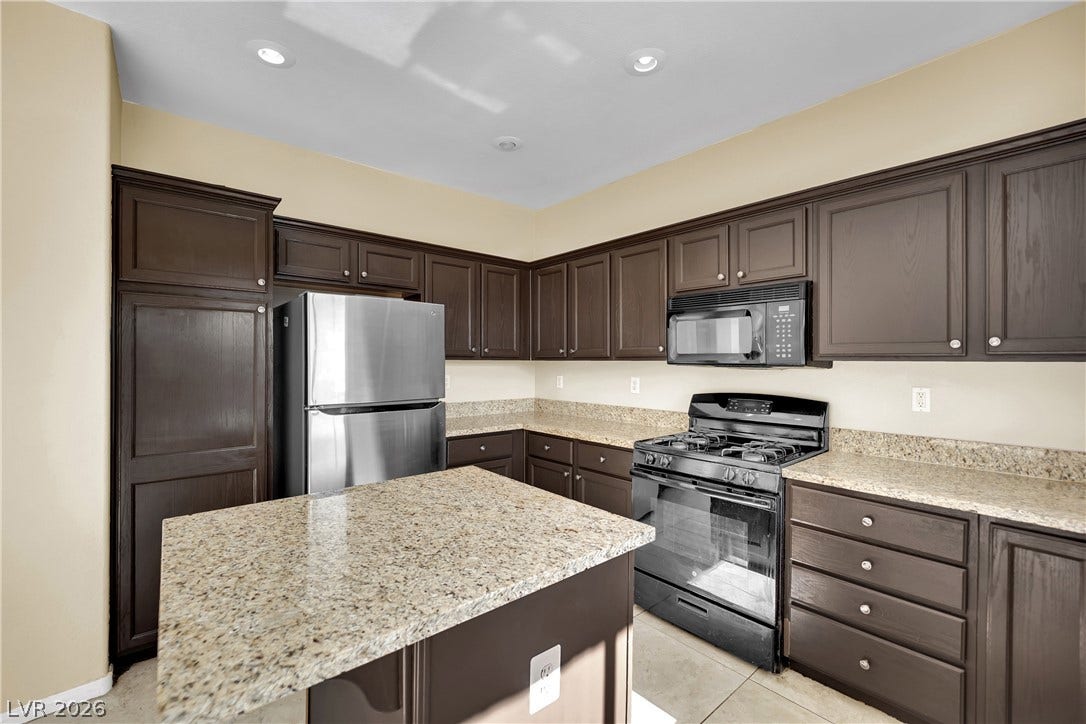 5823 Golden Wing Street, Las Vegas, NV 89113 An inviting kitchen features a central island, rich cabinetry, and a suite of modern appliances, offering both functionality and style.