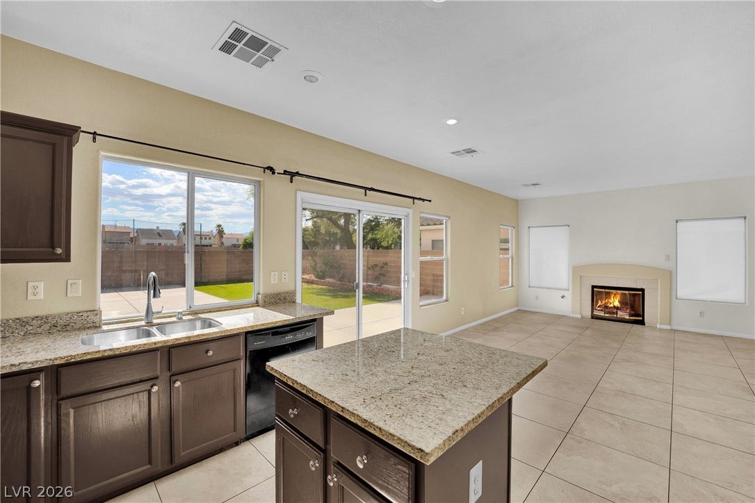5823 Golden Wing Street, Las Vegas, NV 89113 A combined kitchen and living area offers seamless indoor-outdoor living with a cozy fireplace.