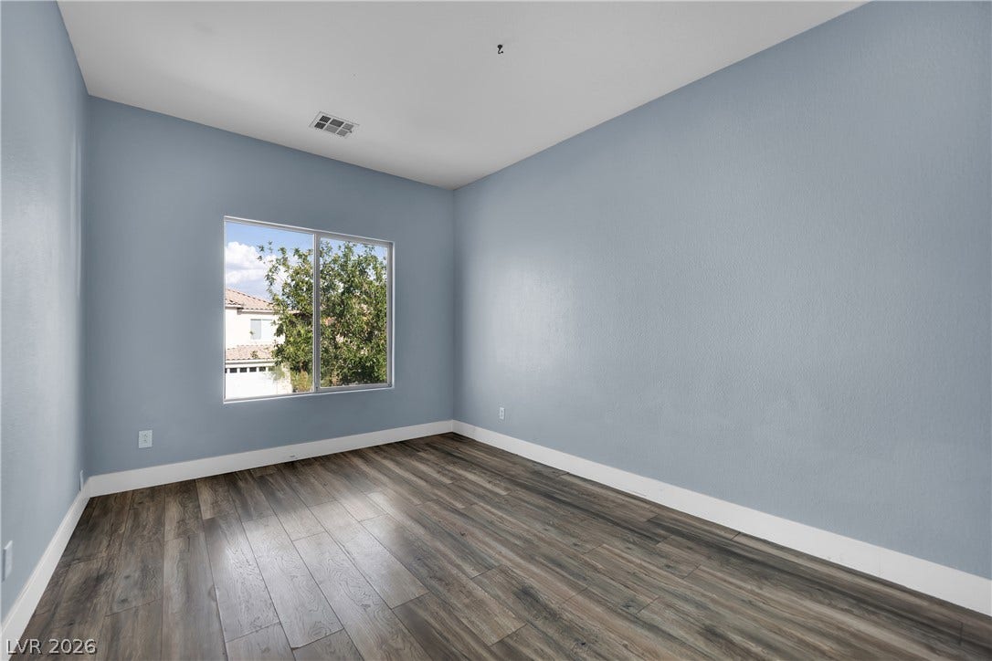 5823 Golden Wing Street, Las Vegas, NV 89113 Well-lit room featuring rich wood flooring and a refreshing tree view through the expansive window.