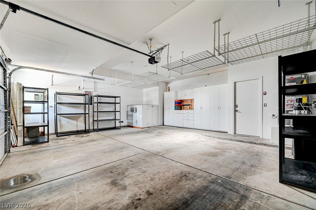 3720 Russell Peterson Court, Las Vegas, NV 89129 A spacious garage features overhead storage racks, built-in cabinetry, and an air conditioned dog house.