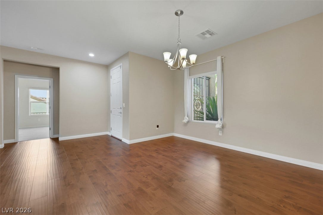 Rich hardwood flooring complements neutral walls, providing a versatile canvas for living or dining.