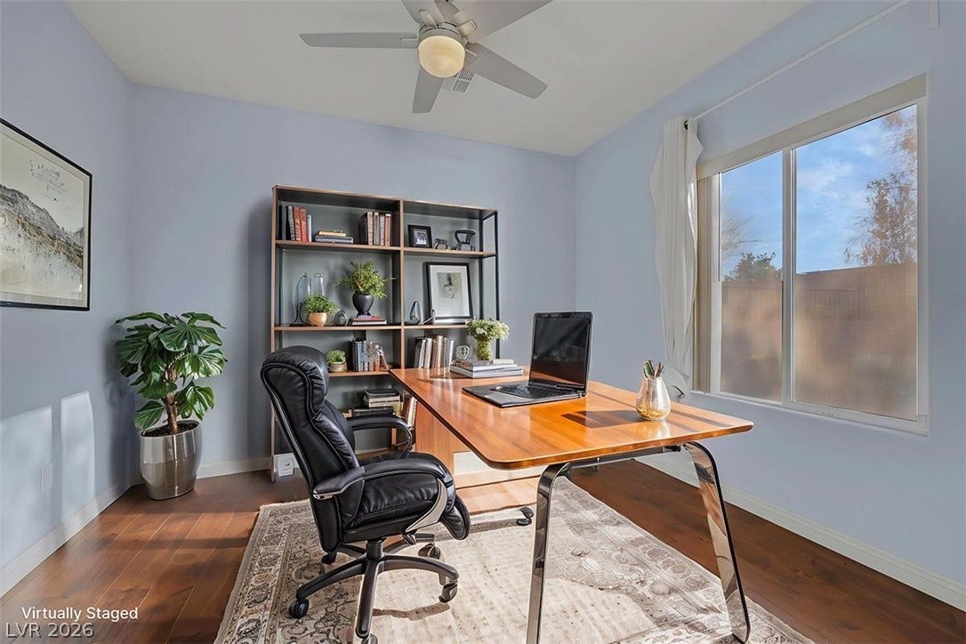 A well-lit home office features rich hardwood flooring and a functional built-in shelving unit, creating an ideal workspace.