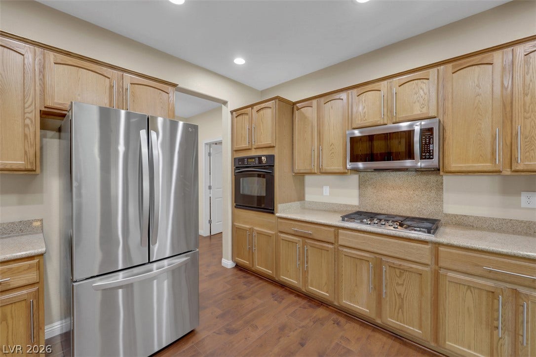 A well-lit kitchen boasts ample cabinetry and contemporary stainless steel appliances, creating an inviting culinary space.