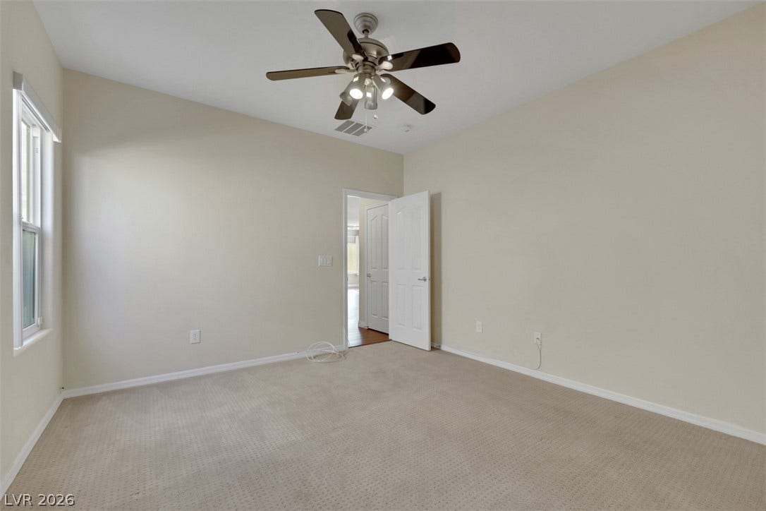 A comfortable bedroom features plush carpeting and a modern ceiling fan, offering a serene retreat.