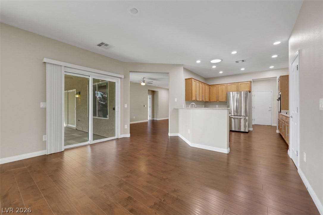 Hardwood floors stretch across this open-concept layout, connecting the living area to a modern kitchen with stainless steel appliances.