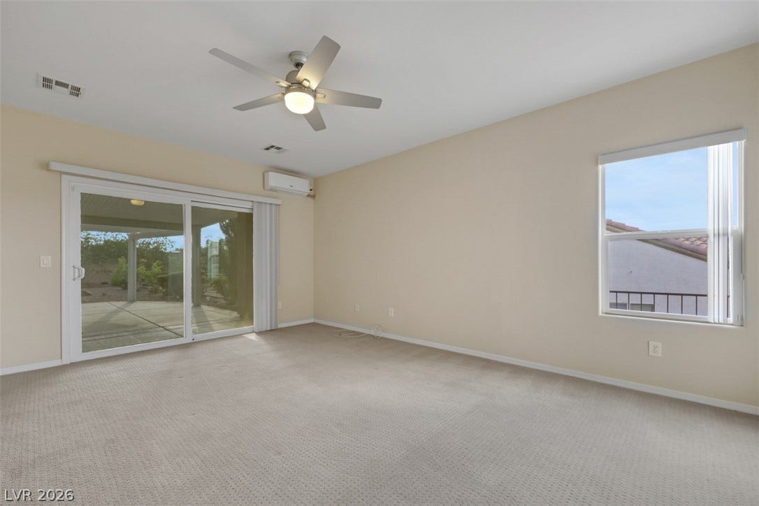 A well-lit bedroom featuring a sliding glass door to the outside and a ceiling fan for comfort.
