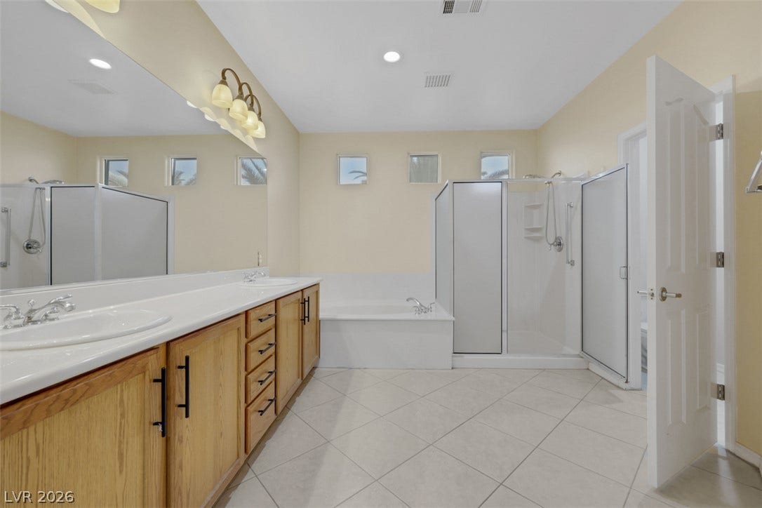 A generously sized bathroom offers dual vanities, a separate shower, and a large soaking tub.
