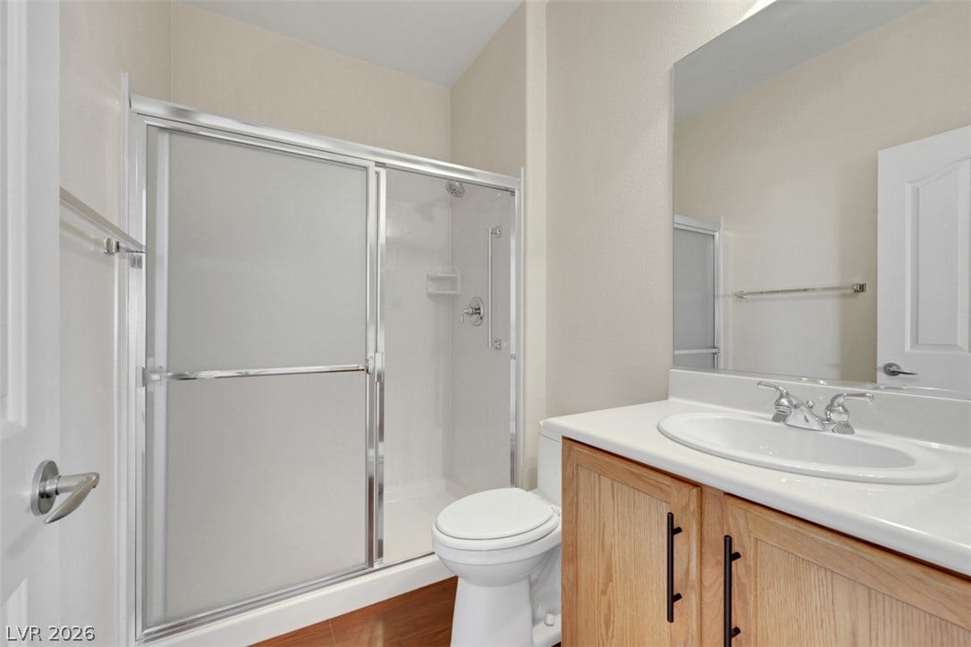 A well-appointed bathroom features a clear glass shower enclosure, wood-toned vanity, and polished chrome fixtures.