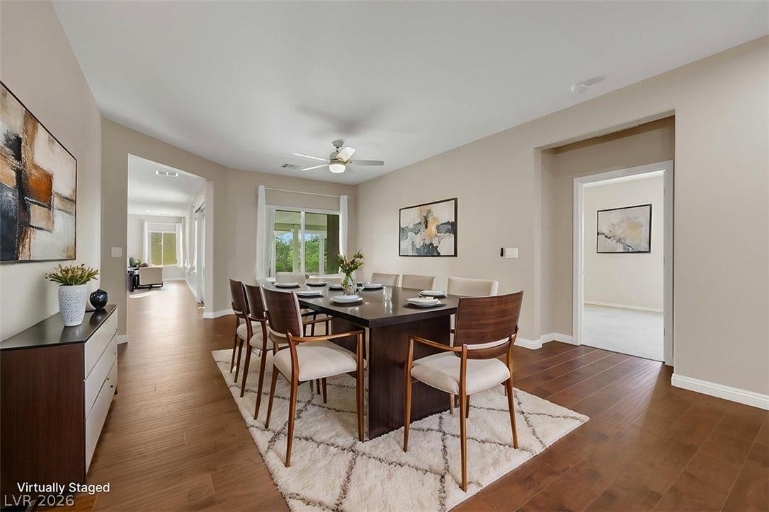 An inviting dining area features rich hardwood flooring and a ceiling fan, opening to a private outdoor space.