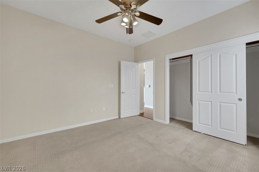 A well-lit bedroom features plush carpeting and a convenient sliding closet door.