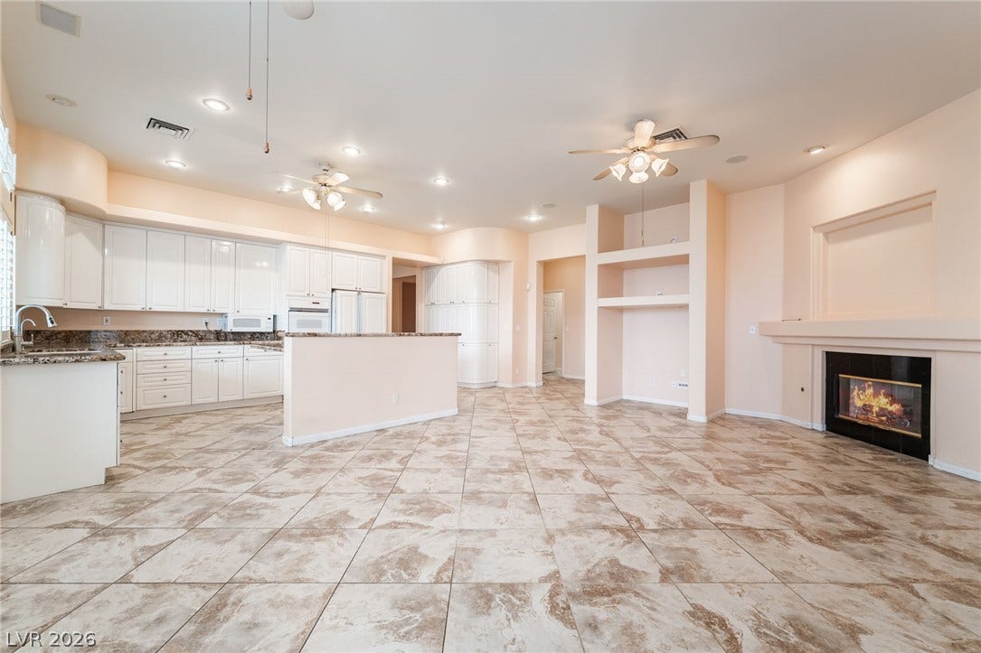 3775 Rick Stratton Drive, Las Vegas, NV 89120 An open-concept living area features a bright kitchen and a cozy fireplace, all beneath recessed lighting and ceiling fans.