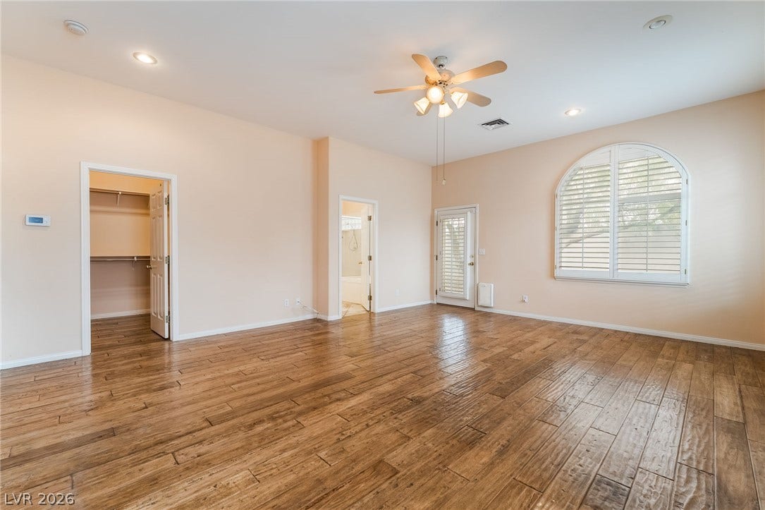 3775 Rick Stratton Drive, Las Vegas, NV 89120 Wood flooring and an arched window illuminate this spacious primary bedroom.