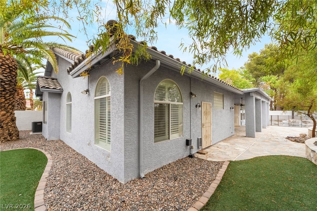 3775 Rick Stratton Drive, Las Vegas, NV 89120 A well-maintained side yard features lush artificial turf and decorative stone accents, leading to a covered patio area.
