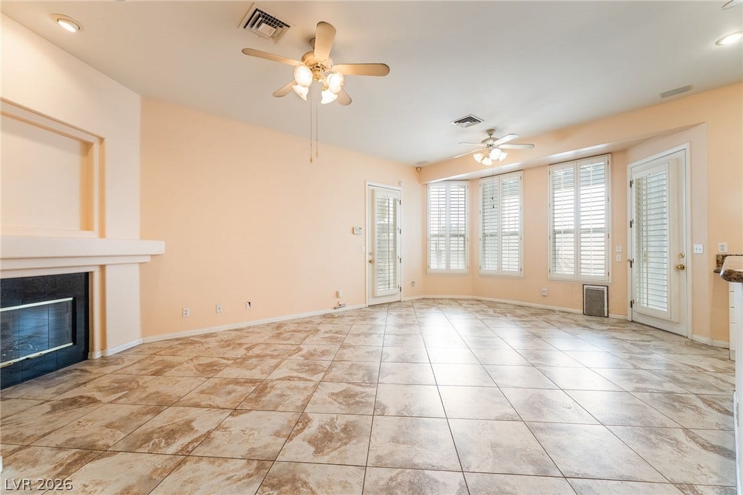 3775 Rick Stratton Drive, Las Vegas, NV 89120 A spacious living area offers cool tile flooring, a cozy fireplace, and abundant natural light from bay windows.