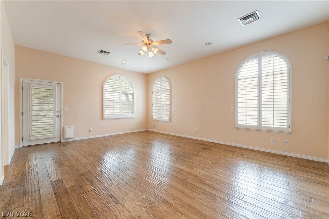 3775 Rick Stratton Drive, Las Vegas, NV 89120 Arch-top windows with shutters illuminate this living area, featuring rich wood flooring and a refreshing ceiling fan.