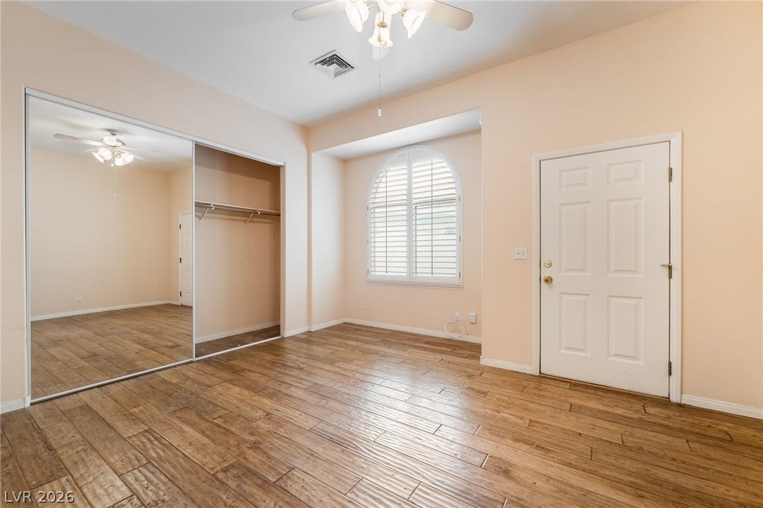 3775 Rick Stratton Drive, Las Vegas, NV 89120 A spacious bedroom features warm wood-look flooring and a mirrored closet, enhancing the open feel.