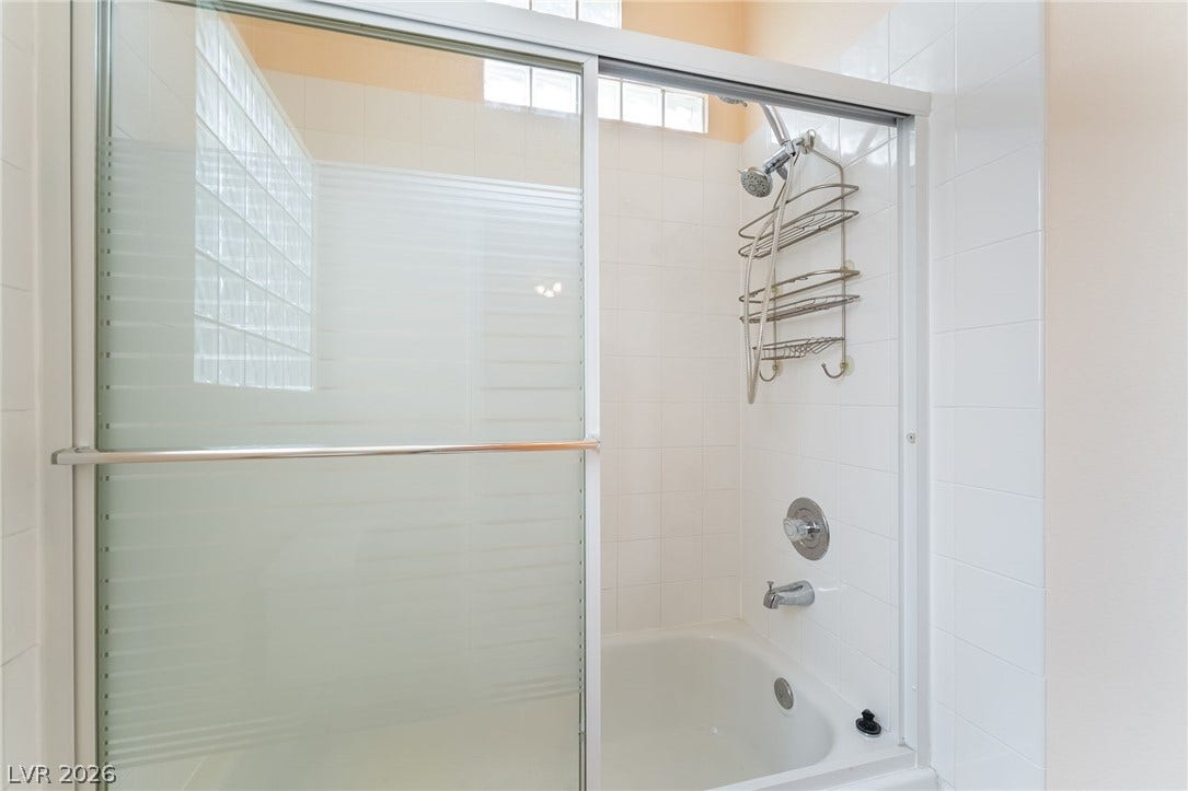 3775 Rick Stratton Drive, Las Vegas, NV 89120 A well-maintained shower and bathtub combination features sleek sliding glass doors and bright tilework.