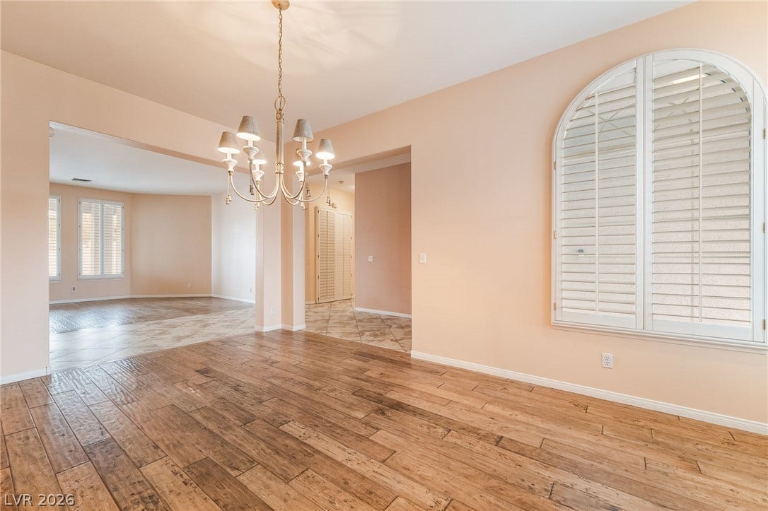 3775 Rick Stratton Drive, Las Vegas, NV 89120 Arch-top windows with shutters illuminate this versatile room, featuring rich hardwood and tile flooring.