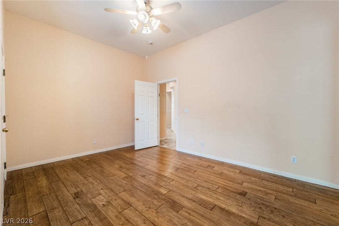 3775 Rick Stratton Drive, Las Vegas, NV 89120 A well-lit bedroom showcasing rich wood flooring and a refreshing ceiling fan.