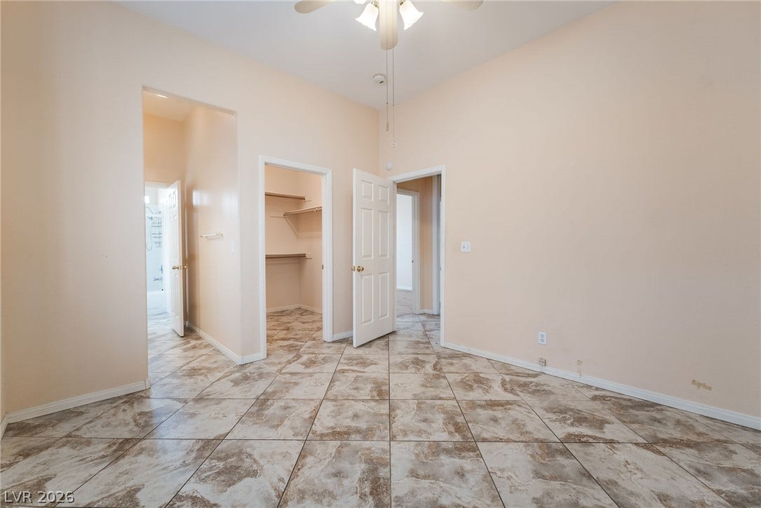 3775 Rick Stratton Drive, Las Vegas, NV 89120 A well-lit room showcasing a ceiling fan, closet, and a clear pathway to an adjacent bathroom.