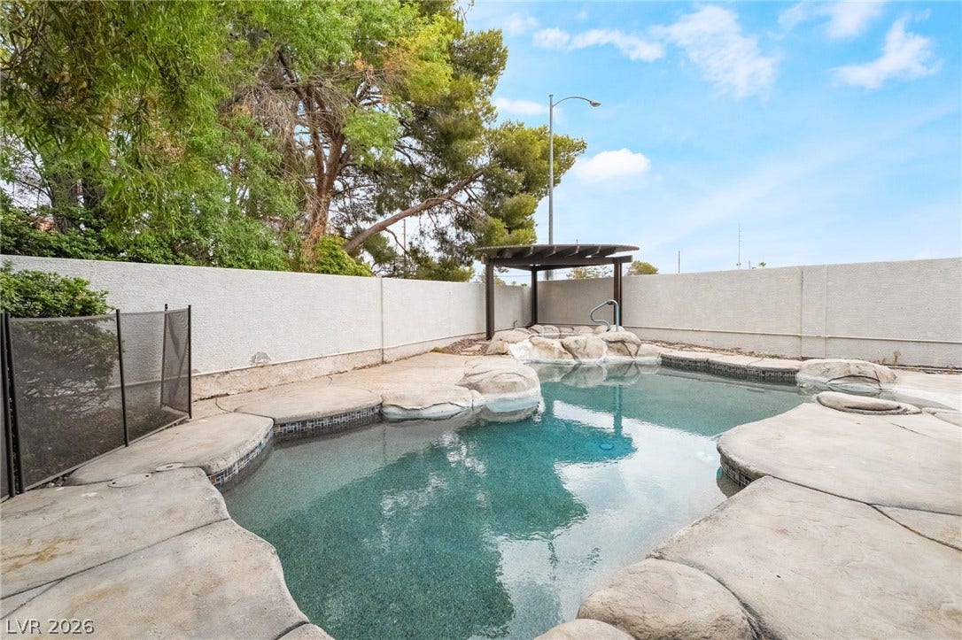 3775 Rick Stratton Drive, Las Vegas, NV 89120 A tranquil backyard oasis features a freeform pool with rock accents and an inviting spa beneath a wooden pergola.