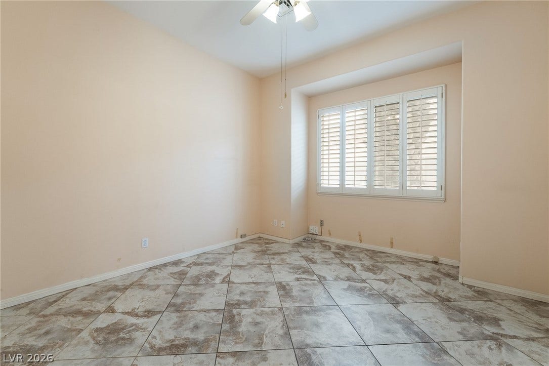 3775 Rick Stratton Drive, Las Vegas, NV 89120 A quiet space features a ceiling fan, tiled floors, and windows with plantation shutters, offering comfort and light.