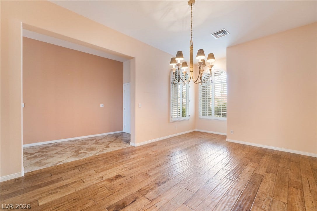 3775 Rick Stratton Drive, Las Vegas, NV 89120 A graceful chandelier illuminates the rich wood flooring of this versatile dining area, with natural light pouring through elegant shuttered windows.