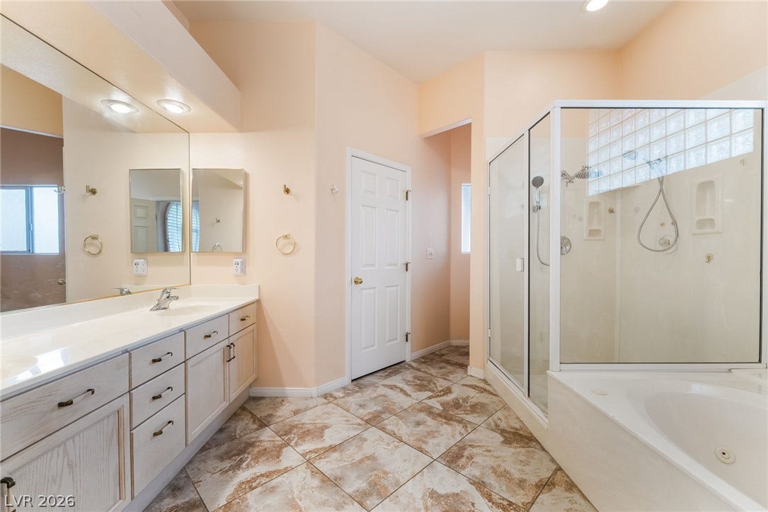 3775 Rick Stratton Drive, Las Vegas, NV 89120 A well-appointed primary bathroom features a double vanity, a glass-enclosed shower, and a soaking tub.