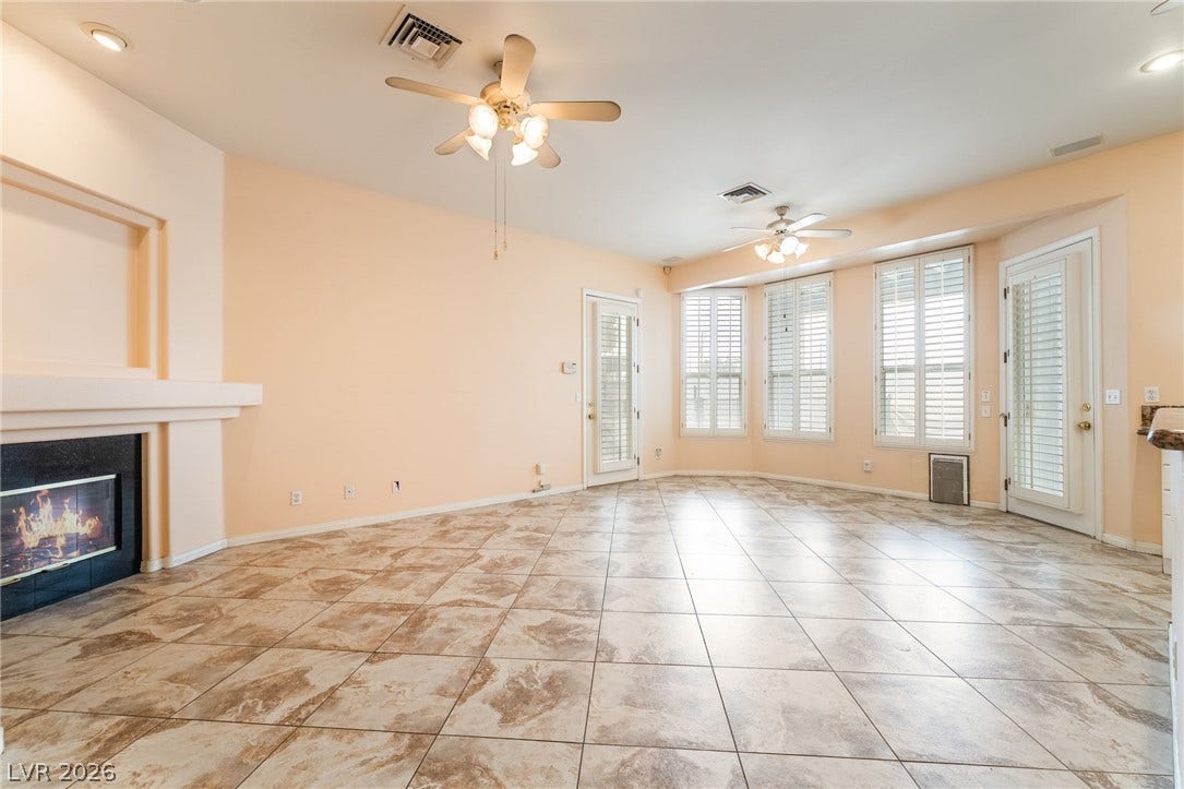 3775 Rick Stratton Drive, Las Vegas, NV 89120 A spacious living area featuring tiled flooring, a cozy fireplace, and abundant natural light from multiple windows.