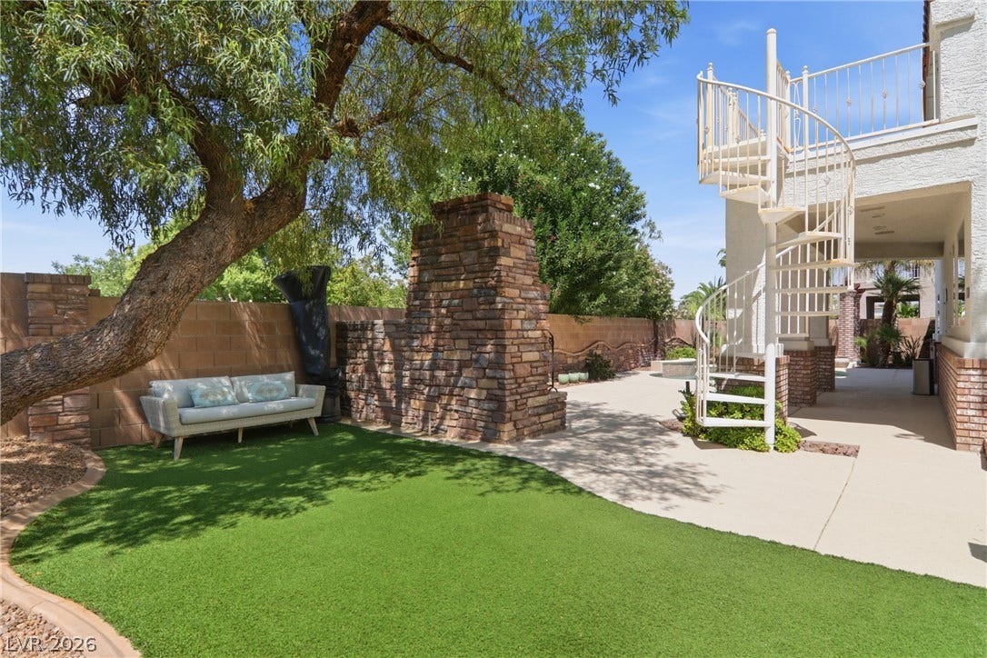 2218 Alanhurst Drive, Henderson, NV 89052 An inviting backyard oasis offers artificial turf, stone masonry, and a charming spiral staircase.