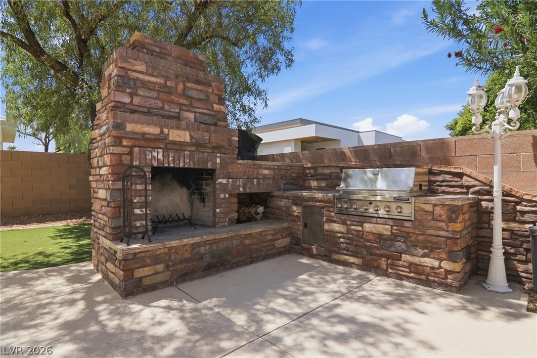 2218 Alanhurst Drive, Henderson, NV 89052 An outdoor living space presents a stone fireplace and built-in barbecue for al fresco entertaining.