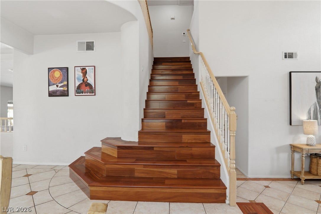2218 Alanhurst Drive, Henderson, NV 89052 Rich wood stairs with a classic banister ascend from a tiled foyer, creating a grand entrance.
